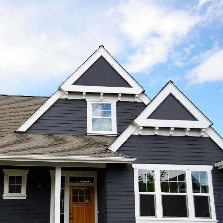 Excalibur Roofing team members in front of a home they just worked on and next to one of their front lawn signs with their logo, phone number, and website link